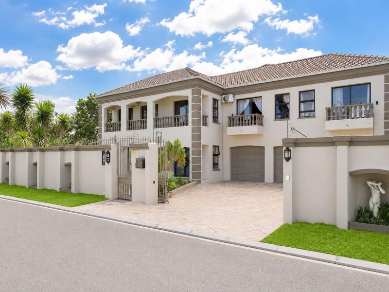 A well-maintained double-story residence featuring a paved driveway, double garage, secure perimeter walling, and upper-level balconies with classic balustrades.