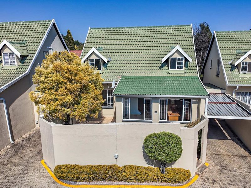 Front elevation of a townhouse featuring a tiled roof, dormer windows, a private paved driveway, and an attached carport.