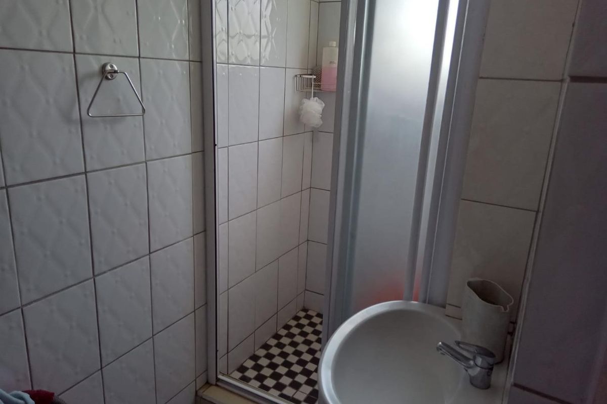 Compact bathroom featuring a shower enclosure with tiled walls and a pedestal basin with a mixer tap.