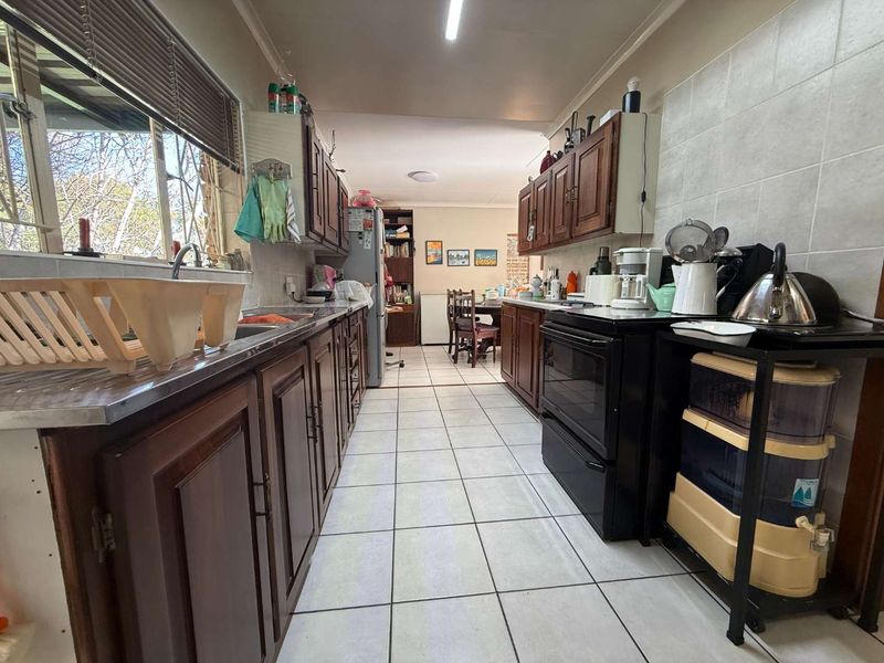 A functional kitchen featuring traditional wooden cabinetry, tiled flooring, and a tiled backsplash, offering a practical layout with direct access to the dining area.