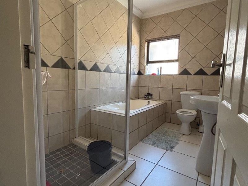A functional bathroom featuring a separate shower enclosure, built-in bathtub, pedestal basin, and toilet with neutral tiled finishes.