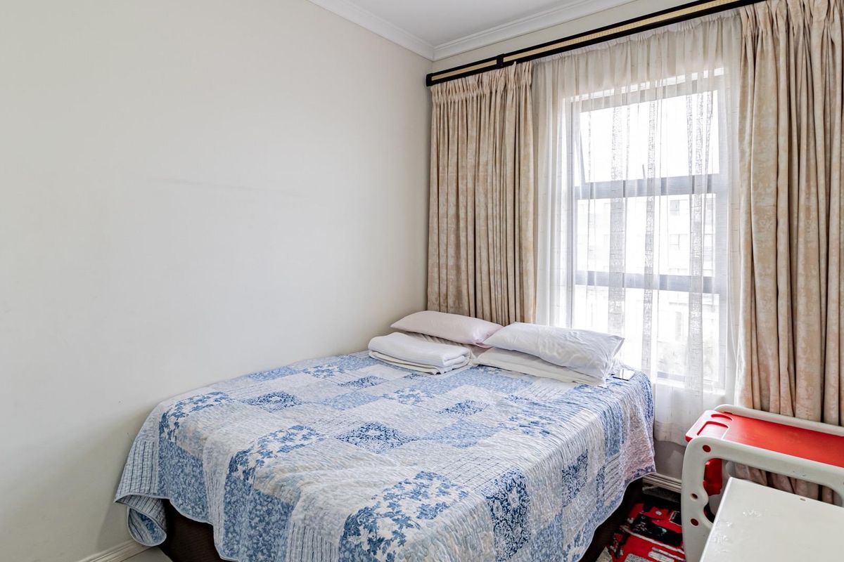 A functional bedroom featuring a window with installed curtain tracks and neutral wall finishes.