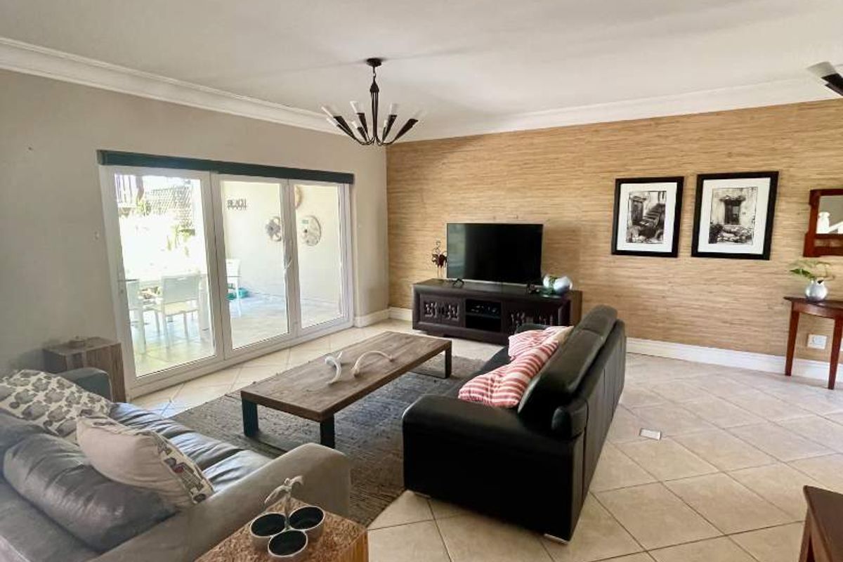 Spacious living room featuring large sliding glass doors leading to an outdoor area, ceramic tiled flooring, and a textured feature wall.