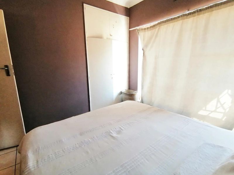A bedroom featuring tiled flooring and a built-in wardrobe, offering a functional space with natural light.