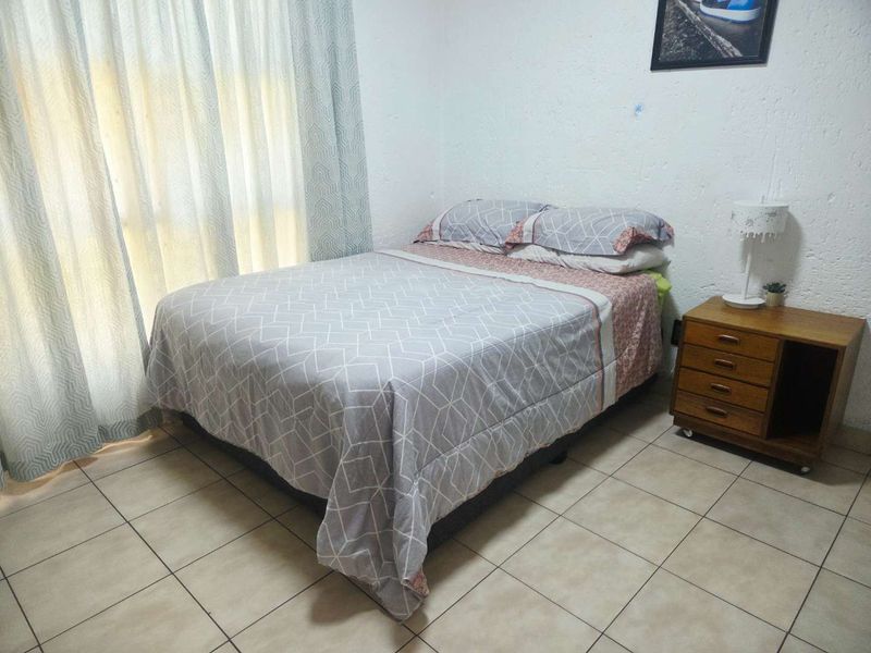 A functional bedroom featuring tiled flooring and textured wall finishes, offering a neutral base for personalization.