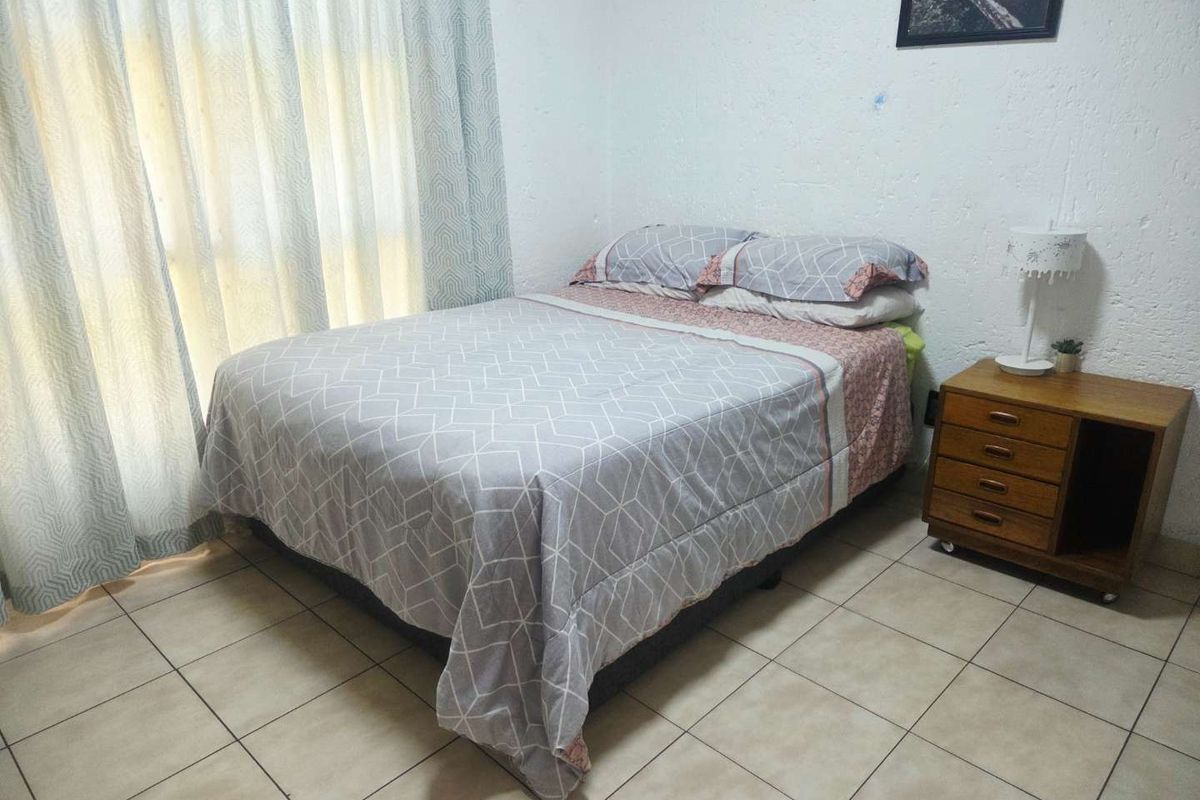 A functional bedroom featuring tiled flooring and textured wall finishes, offering a neutral base for personalization.