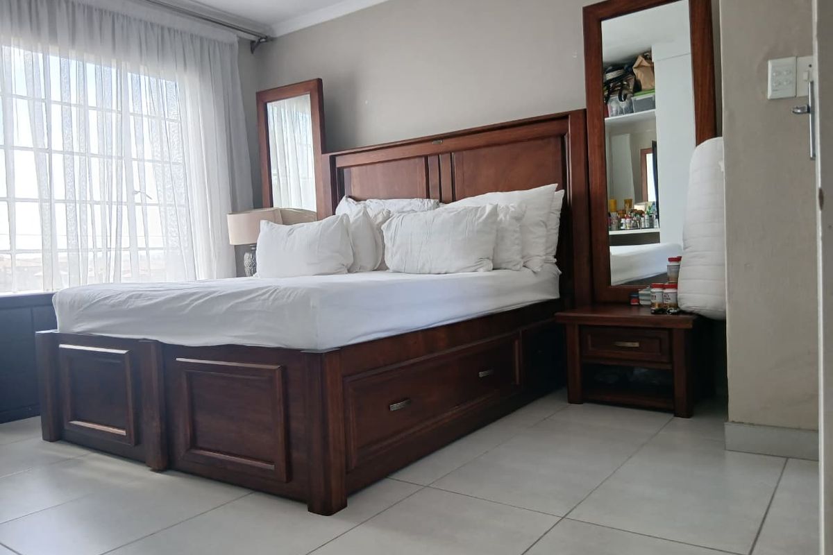 A bedroom featuring tiled flooring and large windows with curtain tracks, providing a functional space with neutral wall finishes.