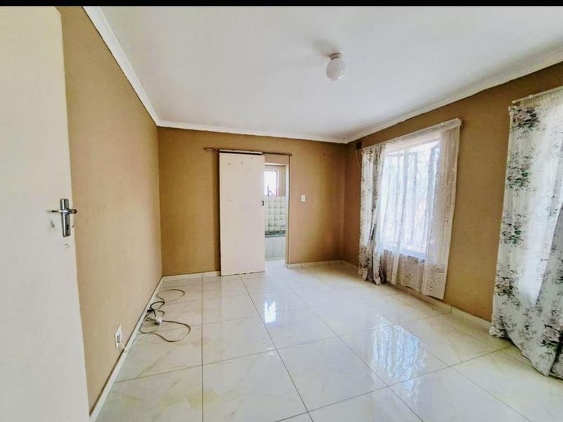 An empty living room featuring tiled flooring, coved ceilings, and a sliding door leading to an adjacent space.