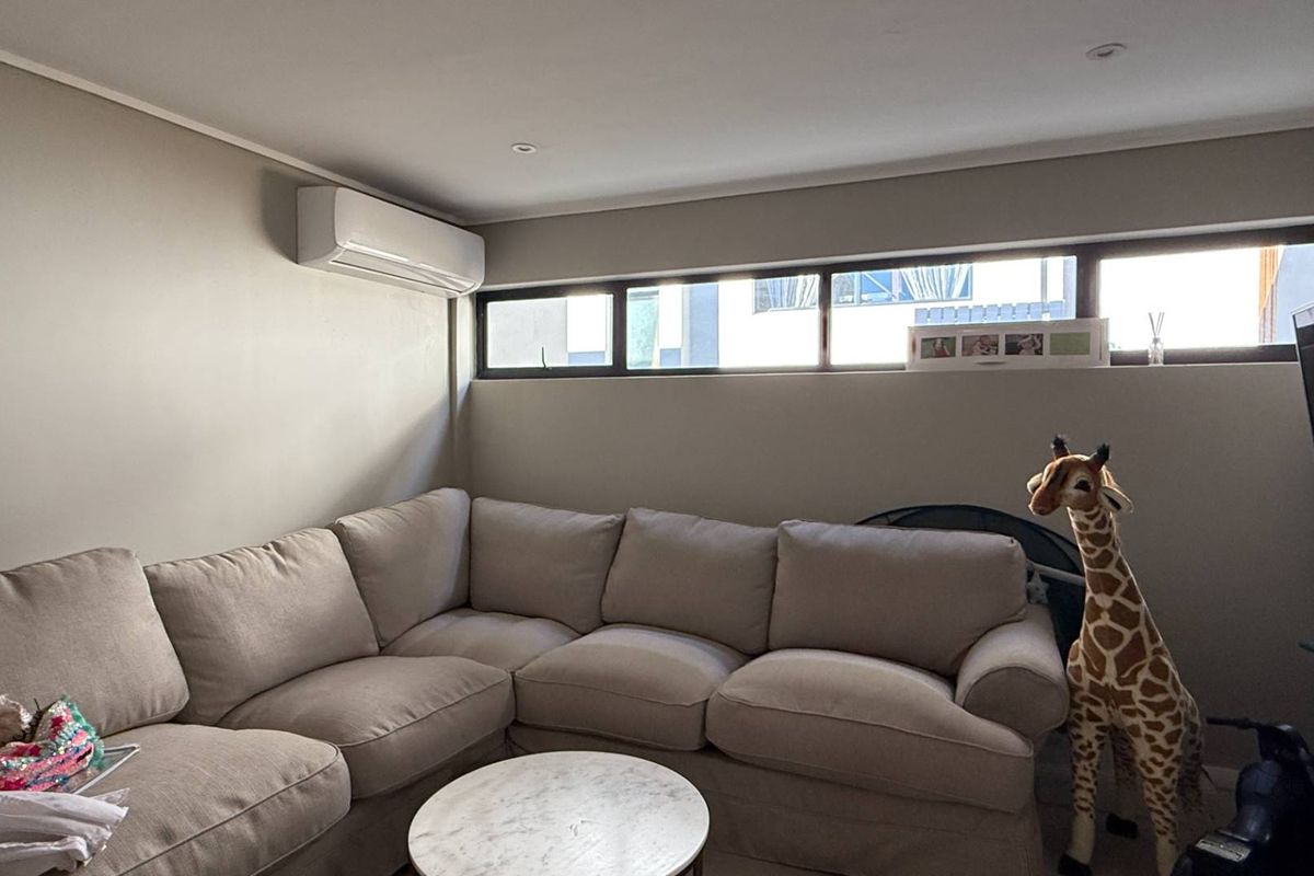 A comfortable living room featuring a wall-mounted air conditioning unit and horizontal clerestory windows providing natural light.