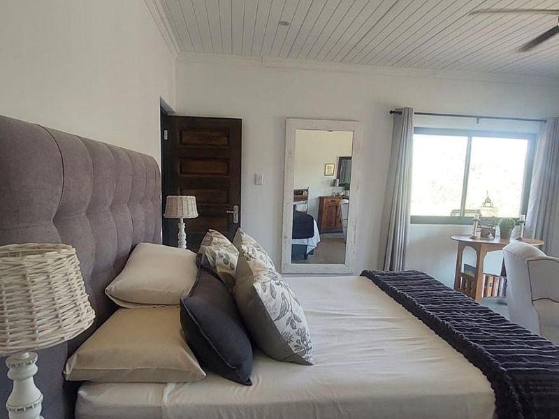 A well-maintained bedroom featuring a white tongue and groove ceiling, ceiling fan, and natural light through a sliding window.