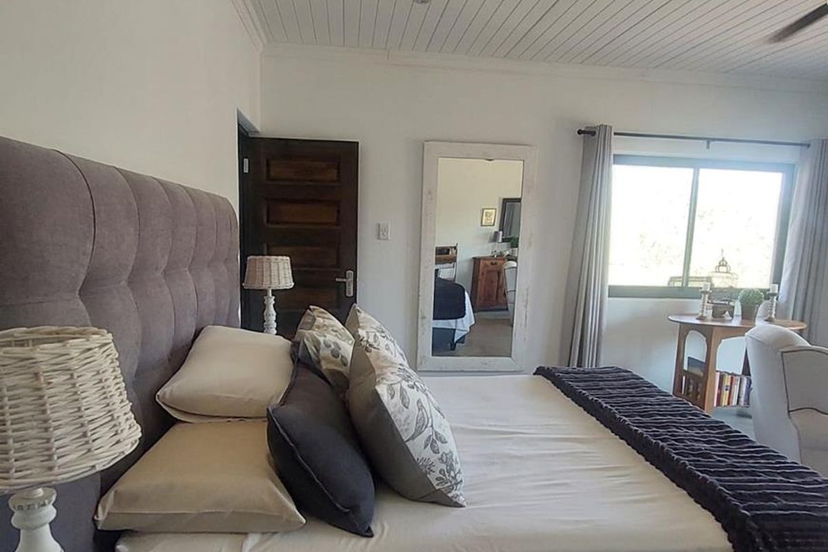 A well-maintained bedroom featuring a white tongue and groove ceiling, ceiling fan, and natural light through a sliding window.