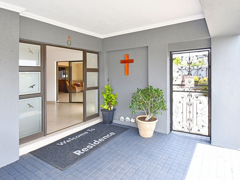 A covered entrance porch featuring paved flooring, a sliding glass door, and a decorative security gate.