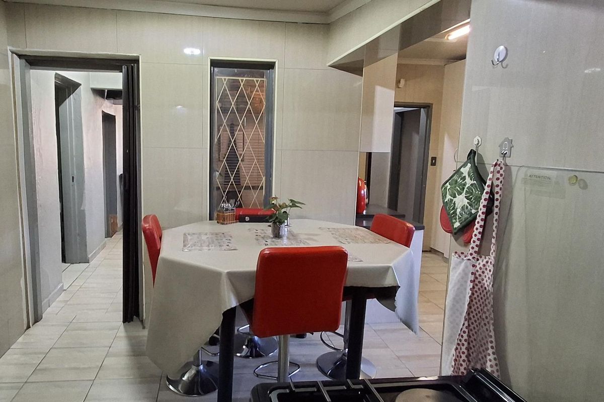 A functional kitchen area featuring tiled walls and flooring, equipped with a gas hob and providing access to adjacent rooms.