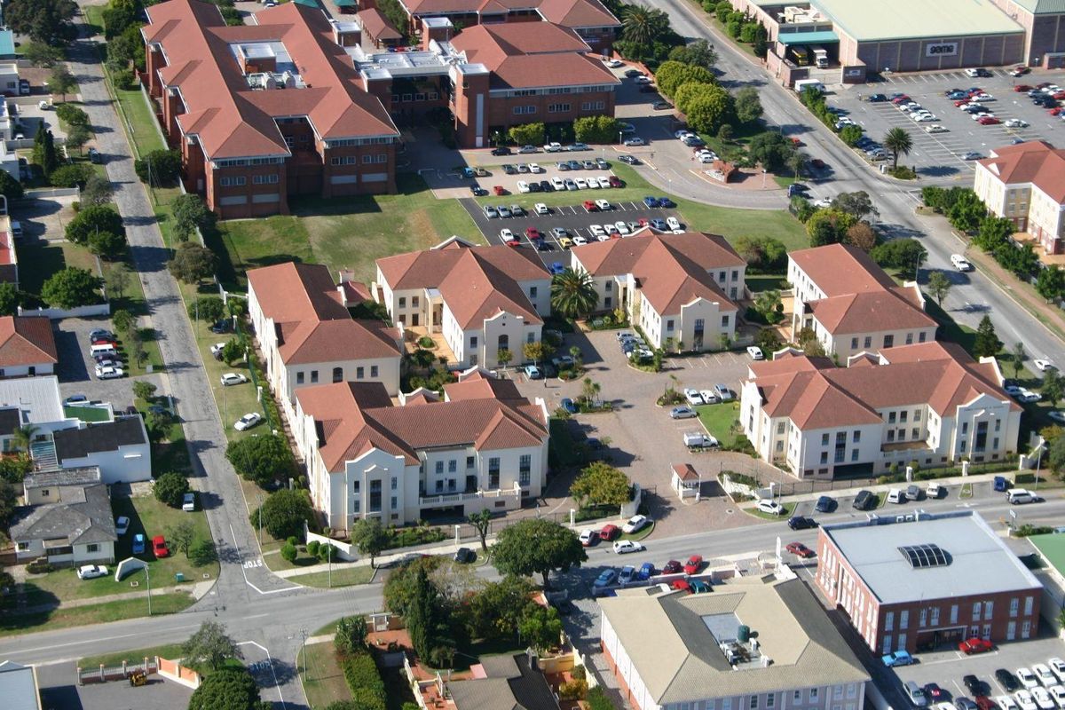 Aerial view of a multi-building office park complex featuring terracotta tiled roofs, paved parking areas, and landscaped grounds.