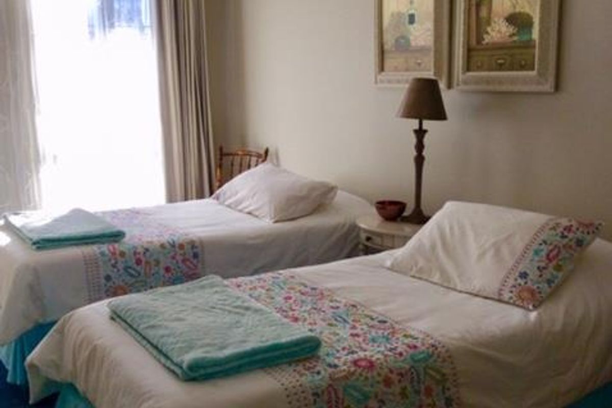 A well-lit bedroom featuring neutral wall tones, crown molding, and a large window with curtain fixtures.