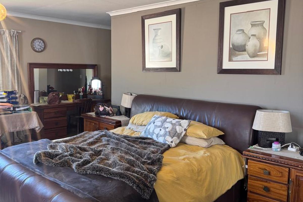 A spacious bedroom featuring tiled flooring and coved ceilings, currently showing signs of wear including visible cracks in the ceiling panels.