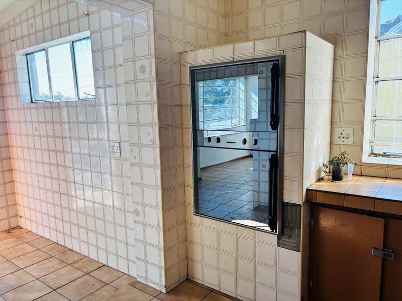 A dated kitchen featuring built-in oven, tiled walls, and tiled flooring, offering a blank canvas for a modern renovation.