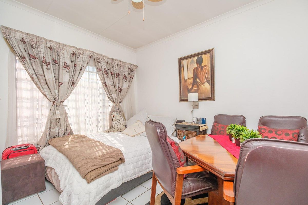 A functional bedroom featuring tiled flooring and a ceiling fan, offering a versatile space with natural light.