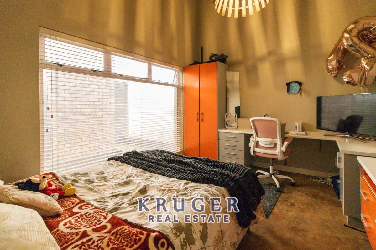 A bedroom featuring large windows with fitted blinds, providing natural light and a functional layout with built-in storage.