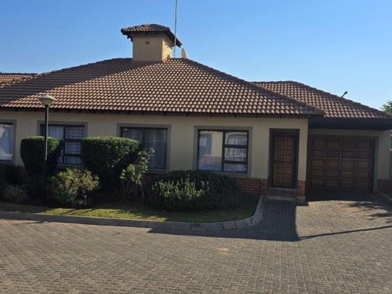 Front elevation of a townhouse featuring a tiled roof, brick driveway, and integrated garage with a secure entrance.