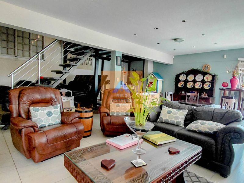 Spacious open-plan living area featuring tiled flooring, recessed lighting, and a prominent staircase with a metal handrail.
