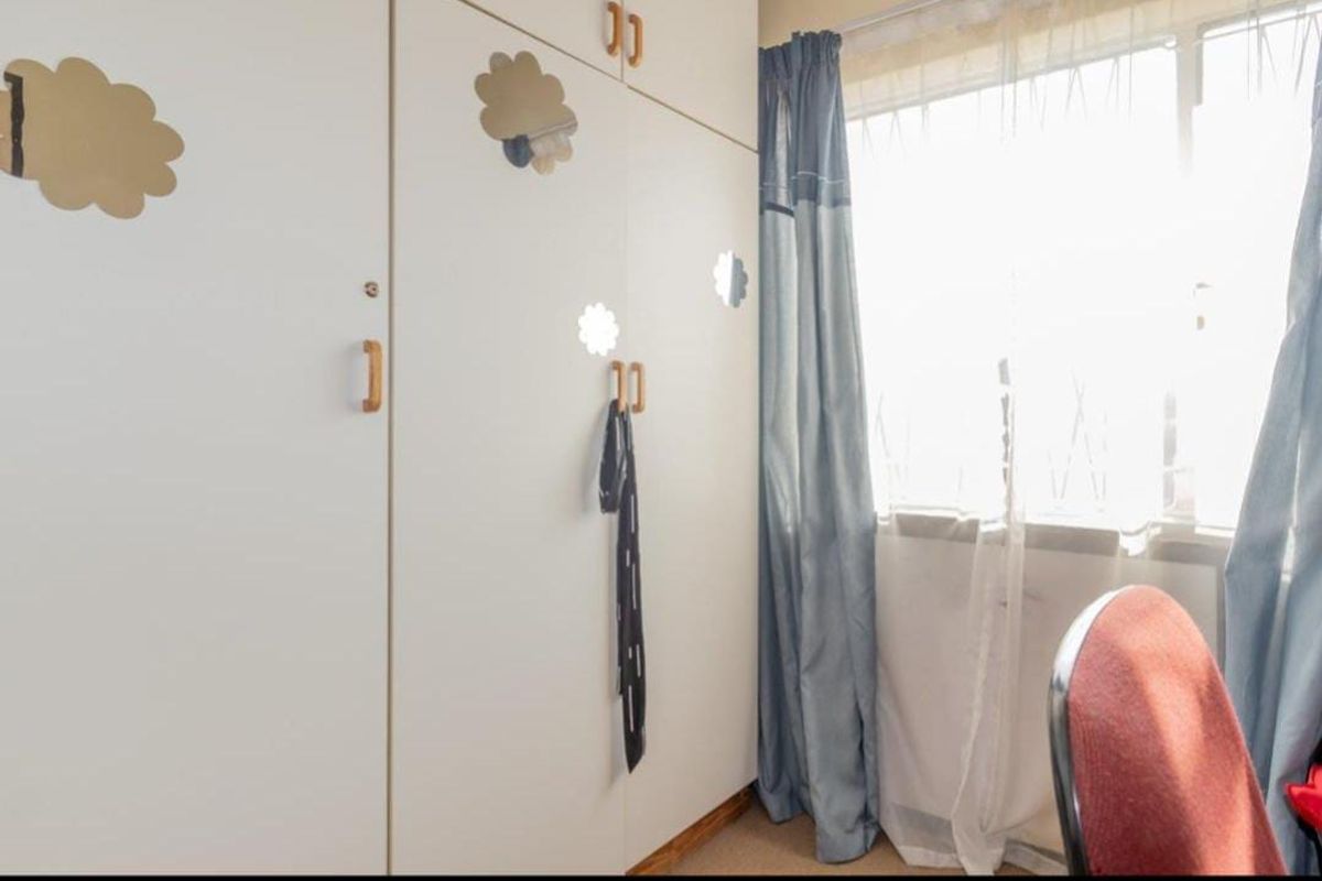 A bedroom featuring built-in cupboards and a large window allowing for natural light.