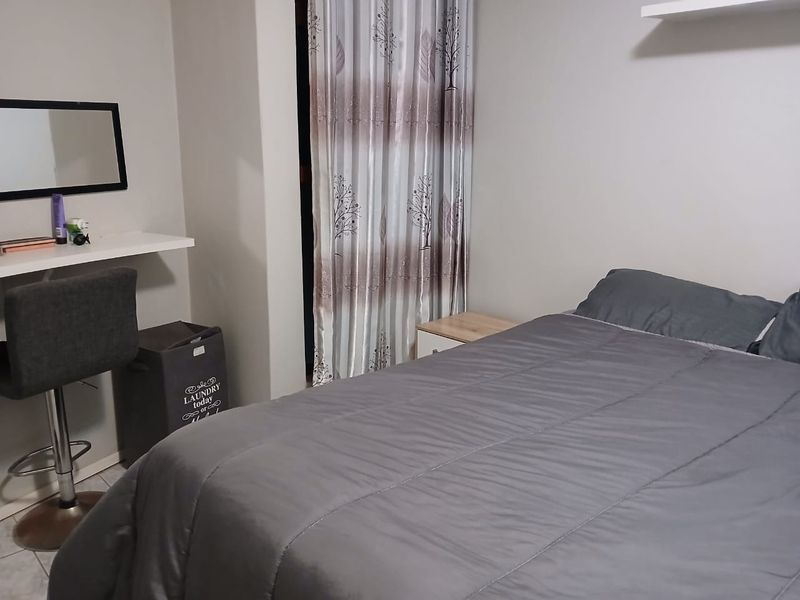 A functional bedroom featuring tiled flooring and a built-in floating shelf, providing a simple and practical living space.