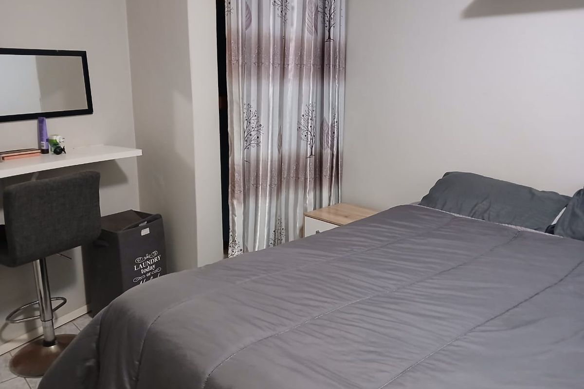 A functional bedroom featuring tiled flooring and a built-in floating shelf, providing a simple and practical living space.