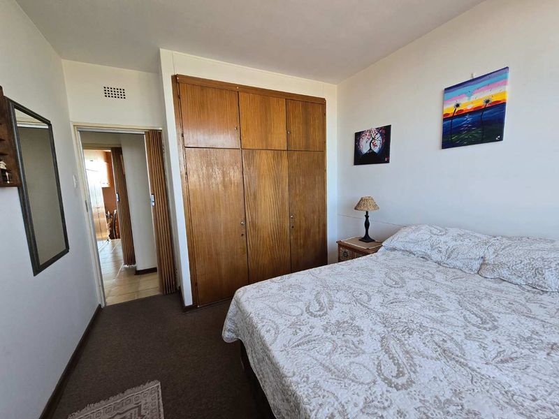 A bedroom featuring built-in wooden wardrobes and carpeted flooring, providing a functional space with potential for modern updates.