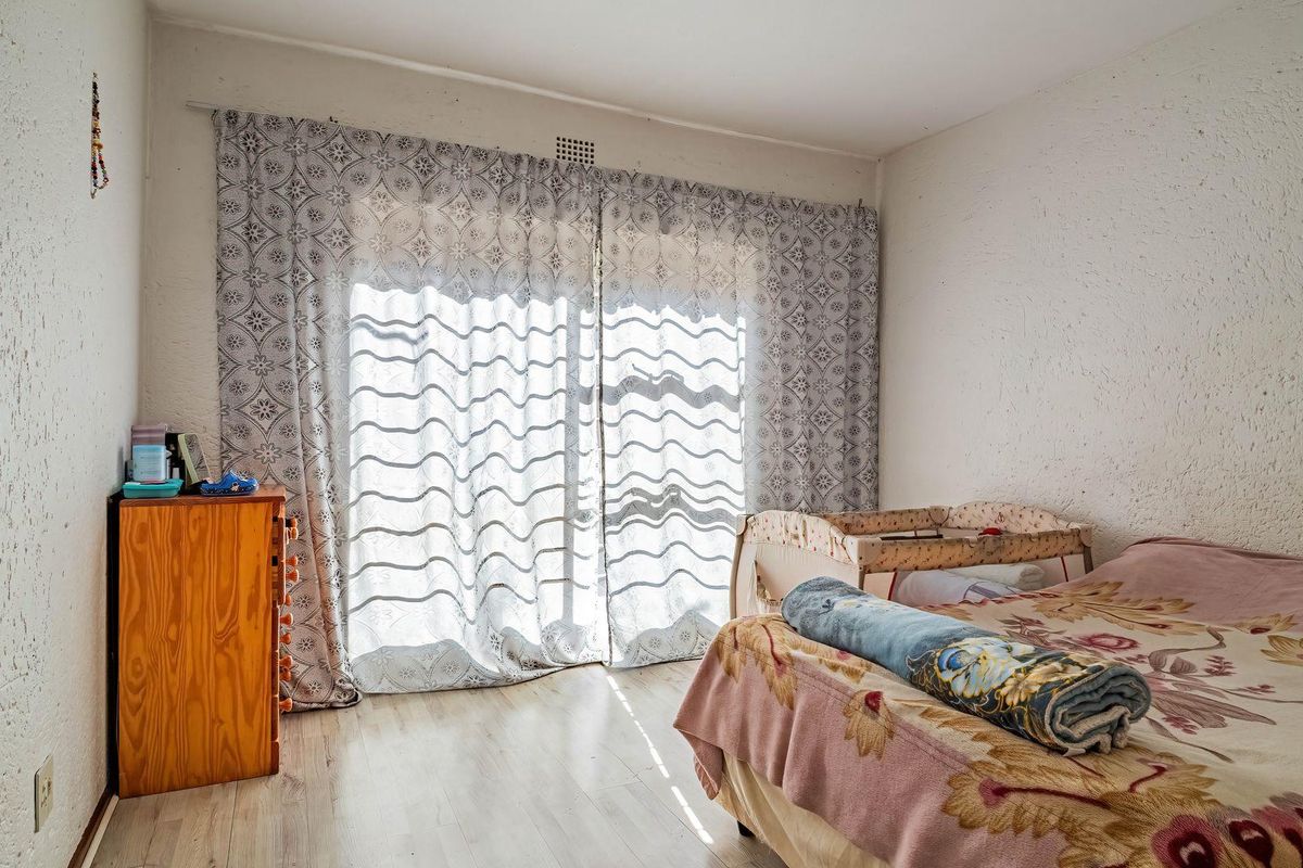 A bedroom featuring textured walls, laminate flooring, and a sliding glass door providing natural light.