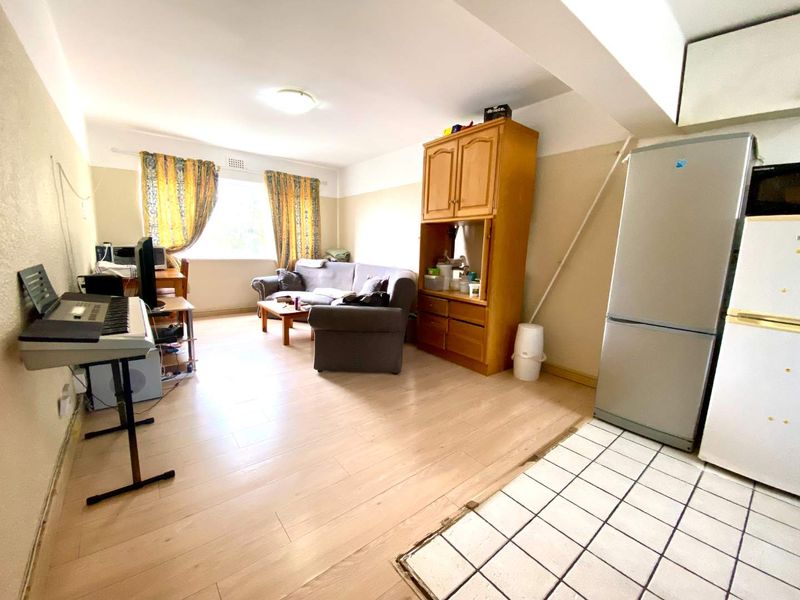 Open-plan living area featuring a combination of laminate and tiled flooring, providing a functional space that integrates living and kitchen zones.
