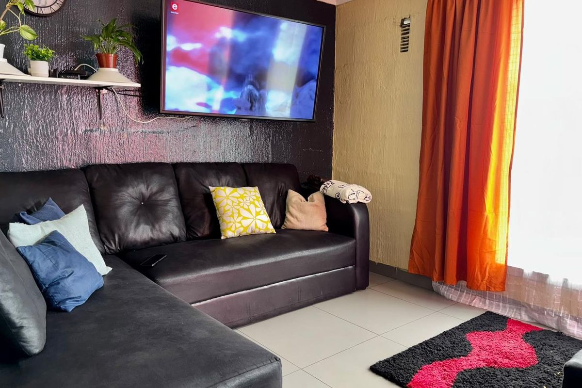 A living room featuring tiled flooring and a dark textured accent wall, providing a functional space for relaxation.