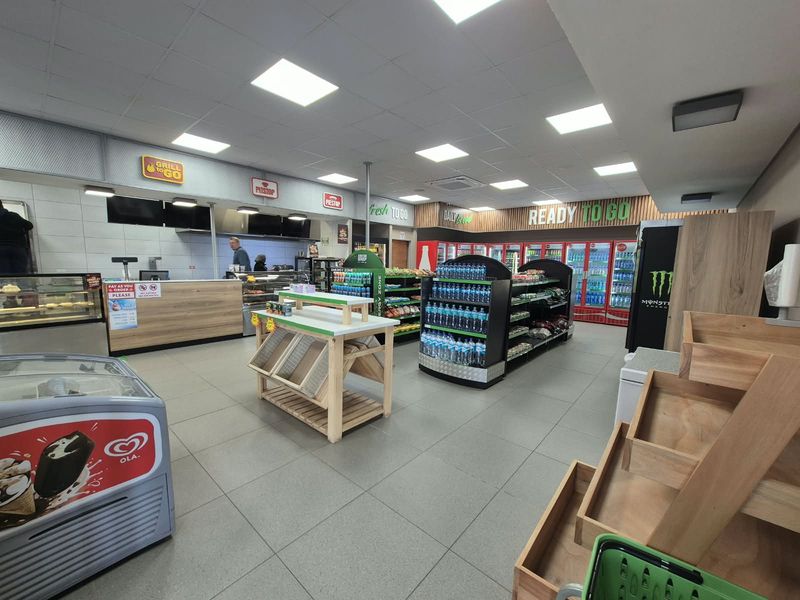A well-maintained commercial retail space featuring tiled flooring, recessed lighting, service counters, and integrated shelving units for product display.