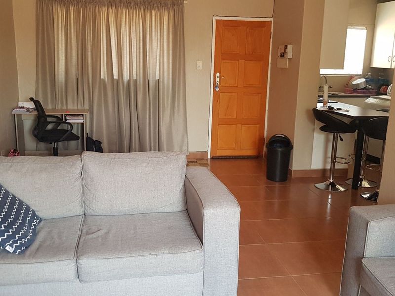 Open plan living area featuring tiled flooring, a functional kitchen with breakfast bar, and direct access to the main entrance.