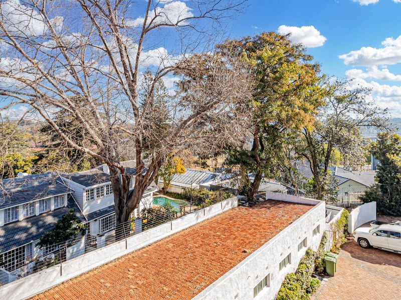 An elevated aerial view of the property showing the roof structure, paved driveway, and surrounding residential landscape.