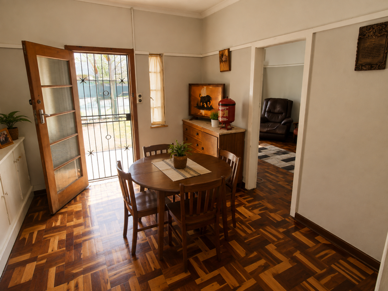 Dining area featuring classic parquet flooring, a timber entrance door with security gate, and direct access to an adjoining living space.