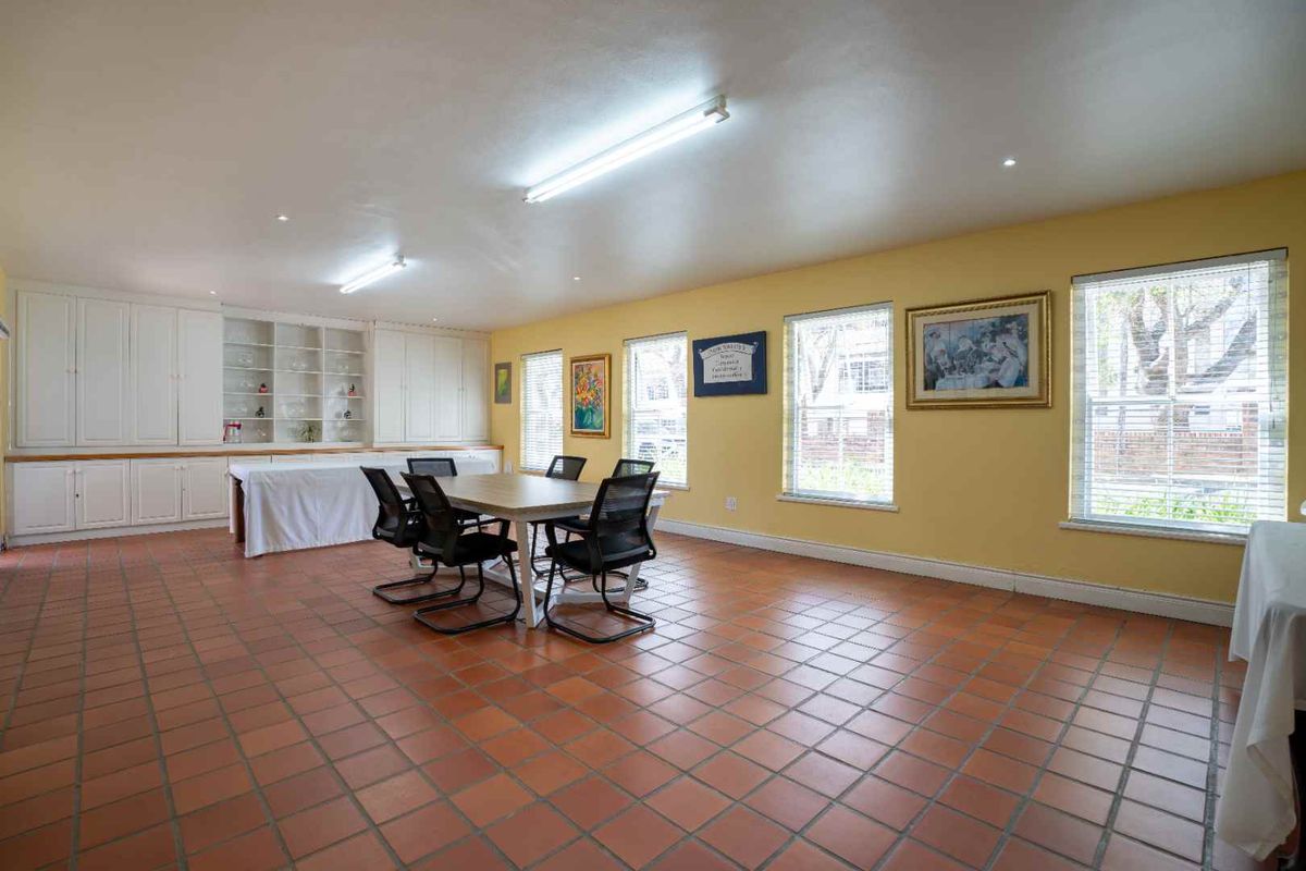 Spacious living area featuring terracotta floor tiles, extensive built-in cabinetry, and a combination of fluorescent and recessed lighting.