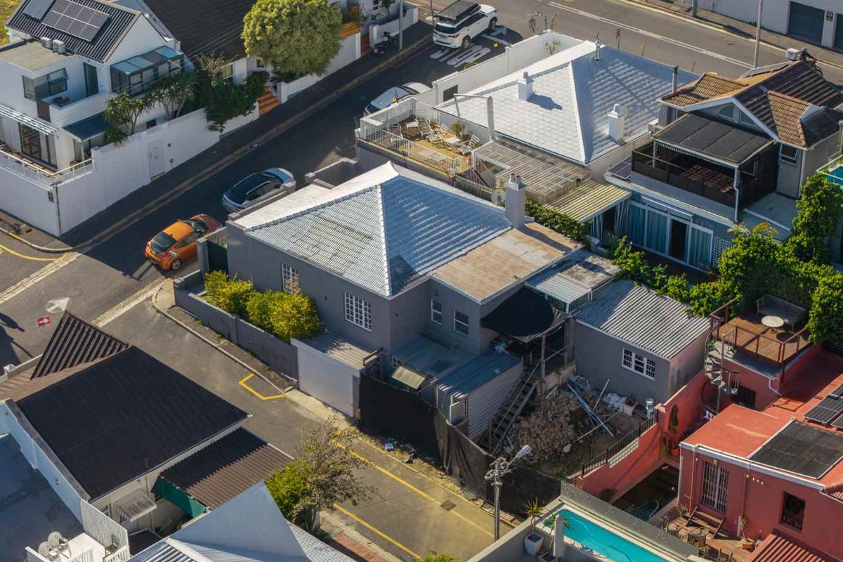 Aerial view of the property showing the roof structure, chimney, and surrounding residential context in a dense urban setting.