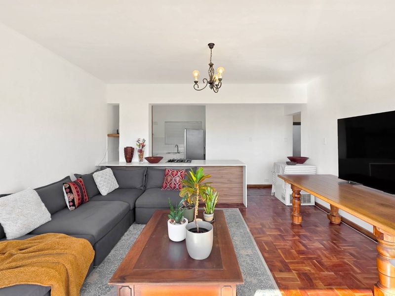 Open-plan living and dining area featuring classic parquet flooring, a breakfast bar, and a functional kitchen layout.