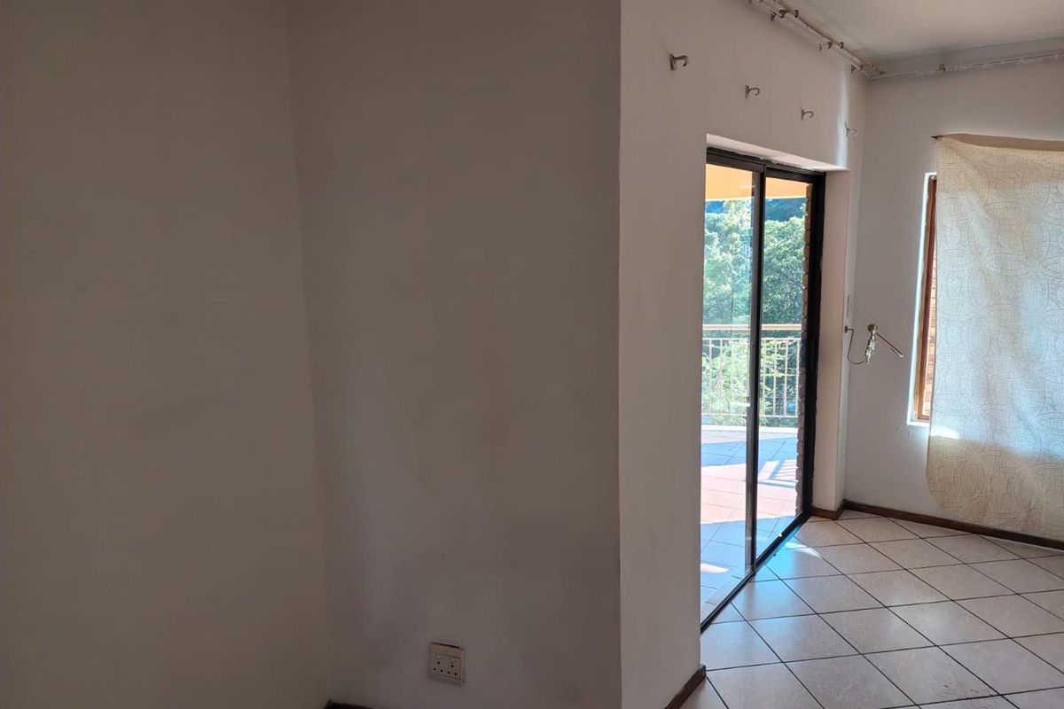 An empty living area featuring ceramic floor tiles and a sliding glass door providing access to an outdoor balcony space.