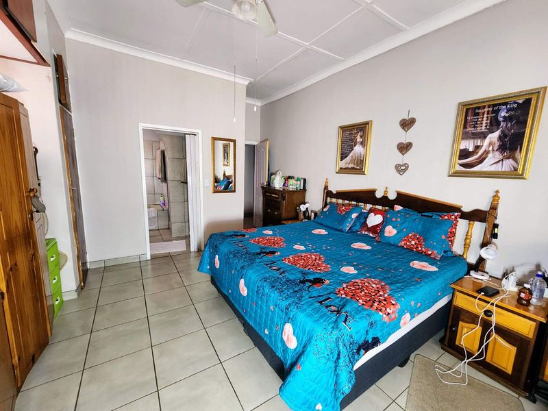 Spacious bedroom featuring tiled flooring, a ceiling fan, built-in cupboards, and convenient access to an en-suite bathroom.