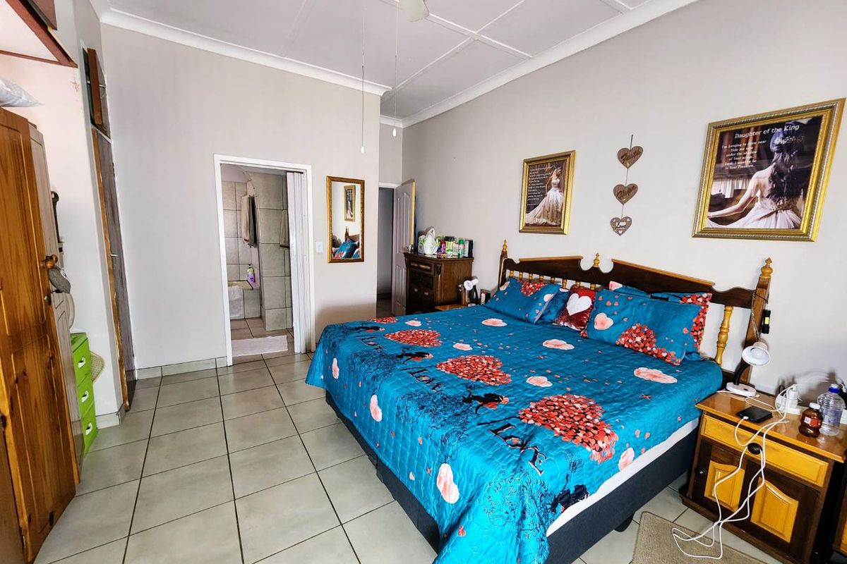 Spacious bedroom featuring tiled flooring, a ceiling fan, built-in cupboards, and convenient access to an en-suite bathroom.