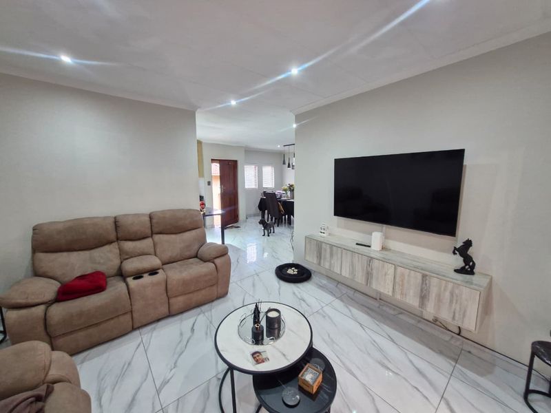 Open-plan living area featuring modern marble-look floor tiles, recessed ceiling lighting, and a sleek wall-mounted floating media console.