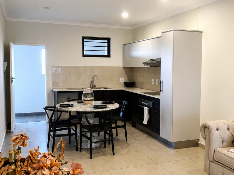 Modern open-plan kitchen featuring sleek cabinetry, built-in oven, extractor fan, and tiled flooring, seamlessly integrated with the living area.