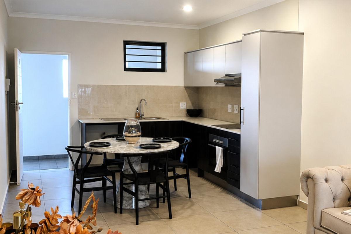 Modern open-plan kitchen featuring sleek cabinetry, built-in oven, extractor fan, and tiled flooring, seamlessly integrated with the living area.