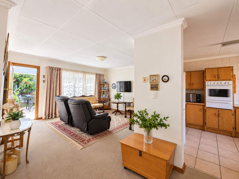 Open-plan living and kitchen area featuring a functional layout, built-in oven, tiled kitchen flooring, and direct access to an outdoor patio space.