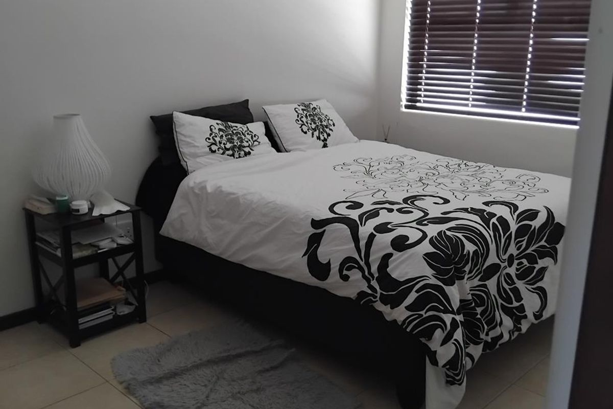 A bedroom featuring tiled flooring and horizontal window blinds.