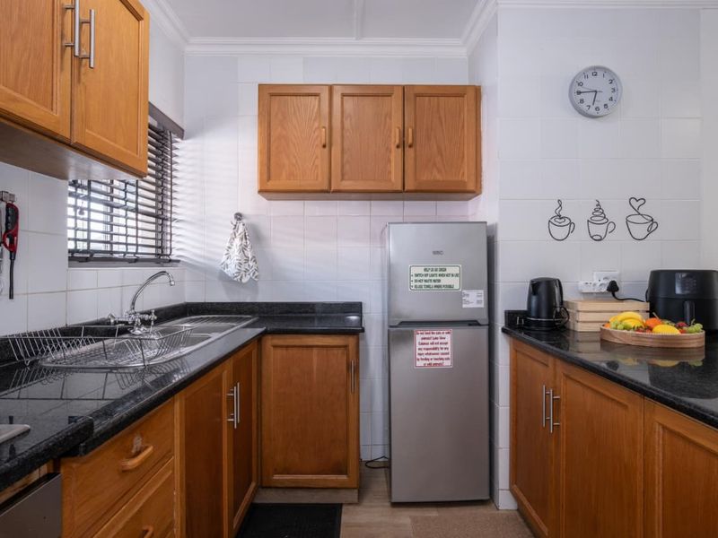 A functional kitchen featuring warm wooden cabinetry, contrasting black granite countertops, and a tiled backsplash, providing a classic and practical workspace.