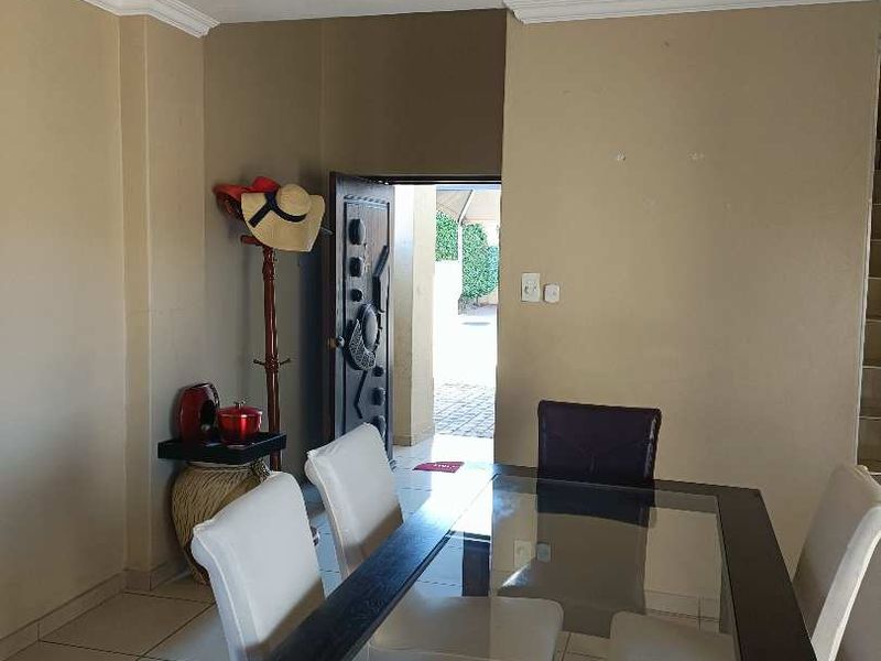 A dining area featuring tiled flooring, recessed lighting, and coved ceiling cornices, with direct access to the exterior through a security gate.