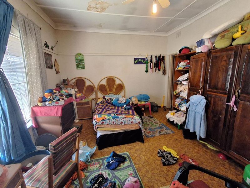 A bedroom featuring a ceiling fan and picture rail, currently showing significant signs of ceiling water damage and wear.